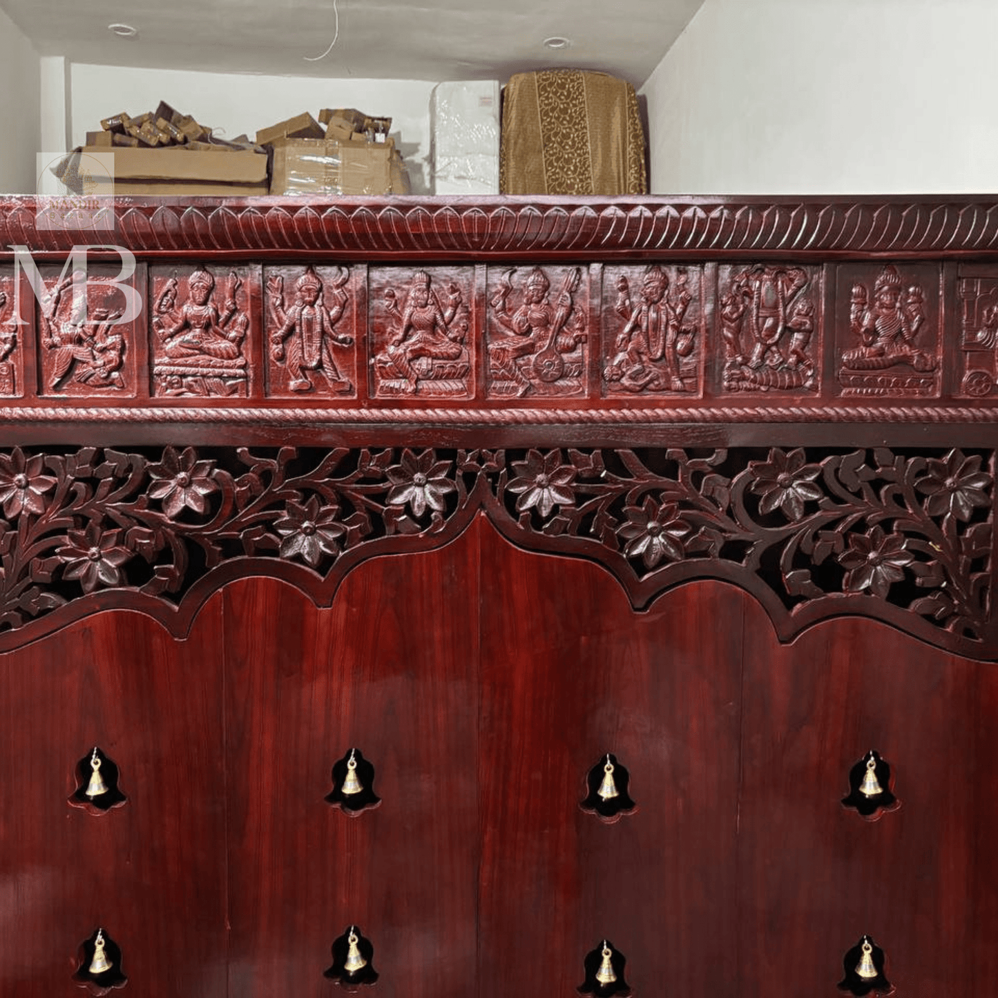 Dark brown wooden pooja mandir with carved floral doors, brass bell details and storage drawers