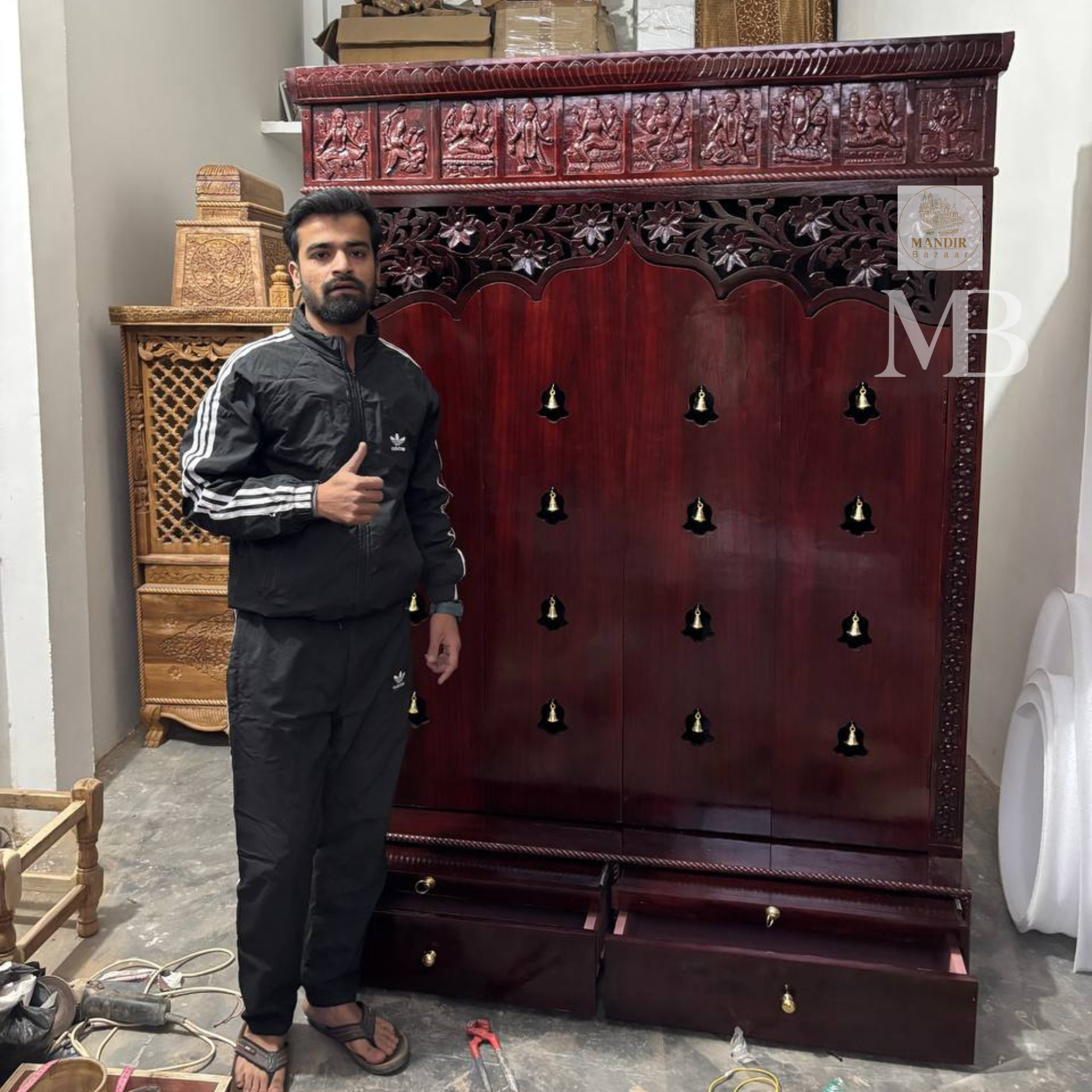 Dark brown wooden pooja mandir with carved floral panels, brass bell accents and spacious storage drawers
