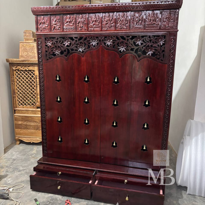 Dark brown wooden pooja mandir with carved floral panels, brass bell accents and spacious storage drawers