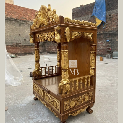 Hand carved wooden pooja mandir in rich brown finish with golden detailing and peacock crown