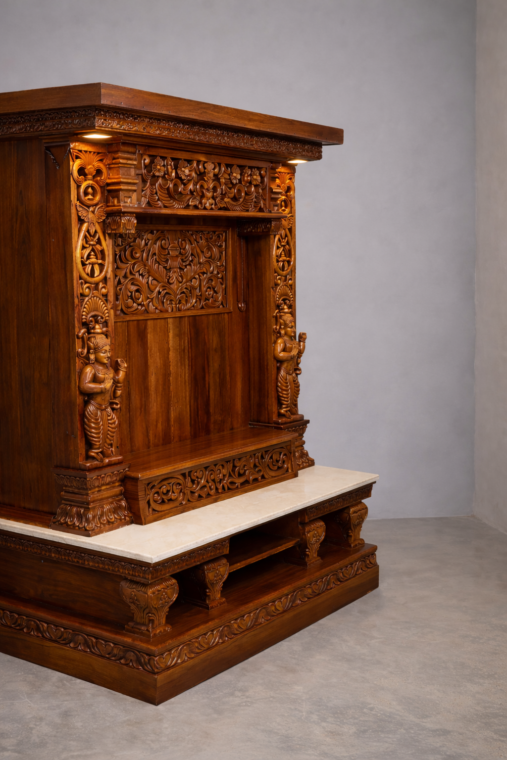 Hand carved wooden pooja mandir with intricate floral carvings, deity figures, marble-look platform and warm LED lights