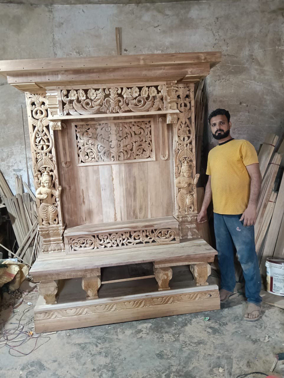 Hand carved wooden pooja mandir with intricate floral carvings, deity figures, marble-look platform and warm LED lights