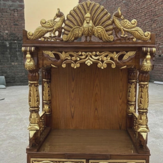 Brown and gold wooden home temple with intricate peacock carving, floral details and carved pillars