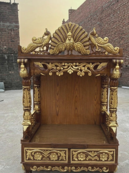 Brown and gold wooden home temple with intricate peacock carving, floral details and carved pillars