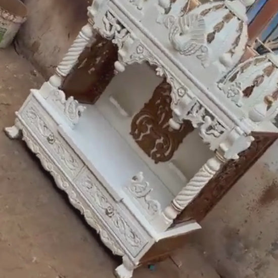 Handcrafted white wooden home temple with gold carved highlights and triple peacock domes