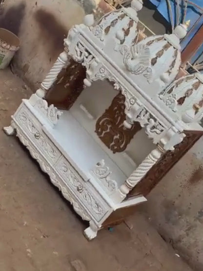 Handcrafted white wooden home temple with gold carved highlights and triple peacock domes