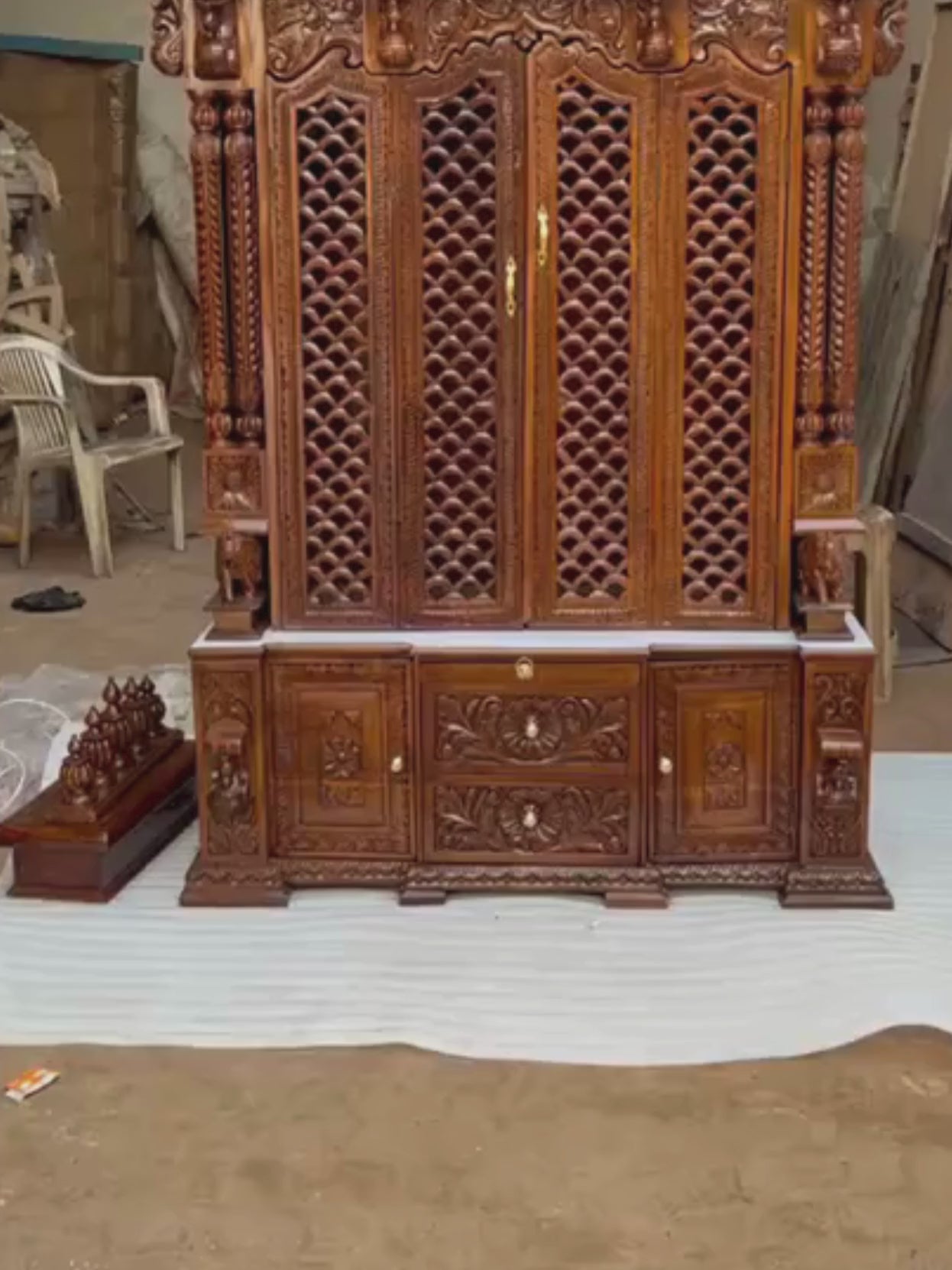 Bottom storage cabinet featuring floral carved drawers and side doors on antique Sheesham wooden temple