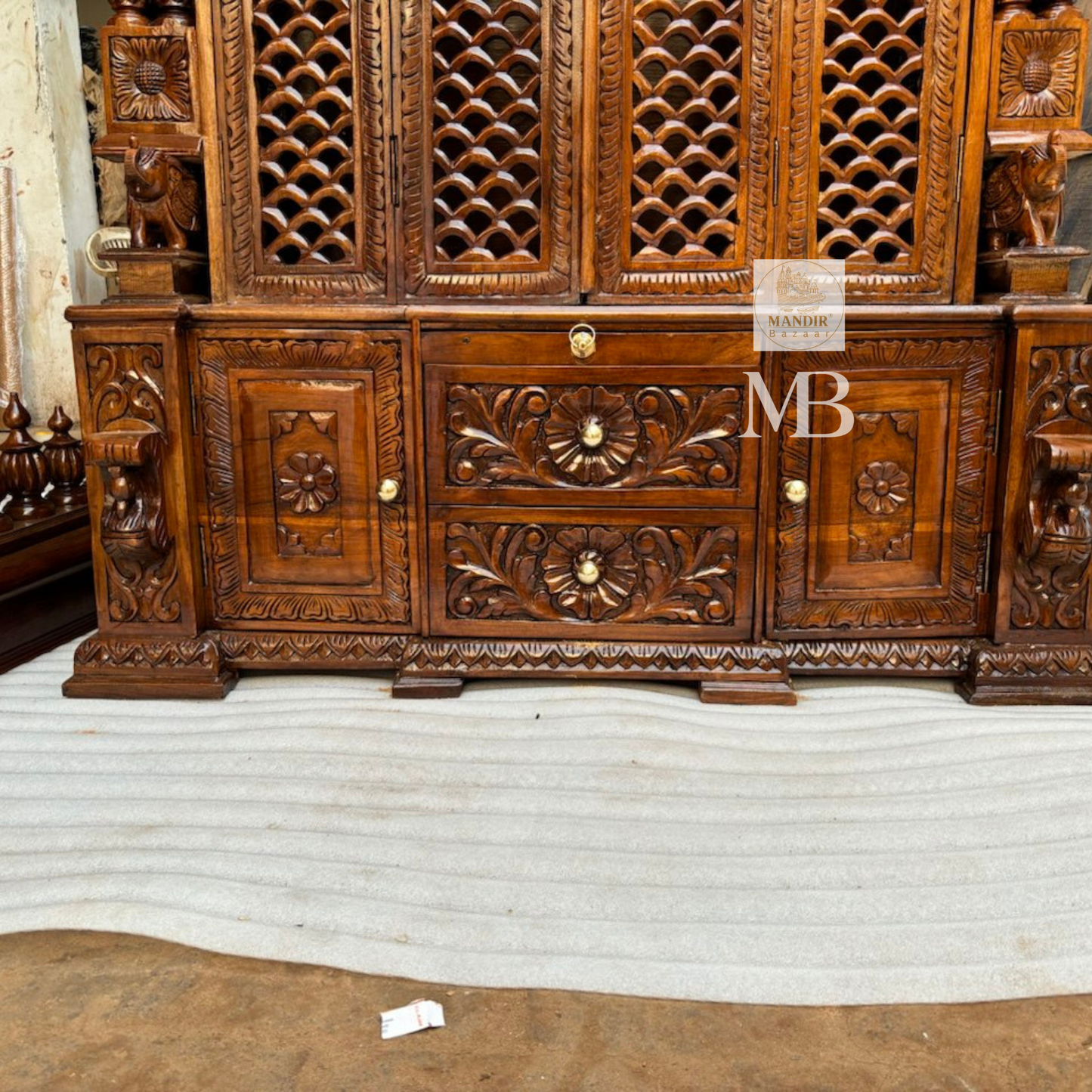 Detailed close-up of hand-carved floral top crown and elephant pillar base on Sheesham wood mandir