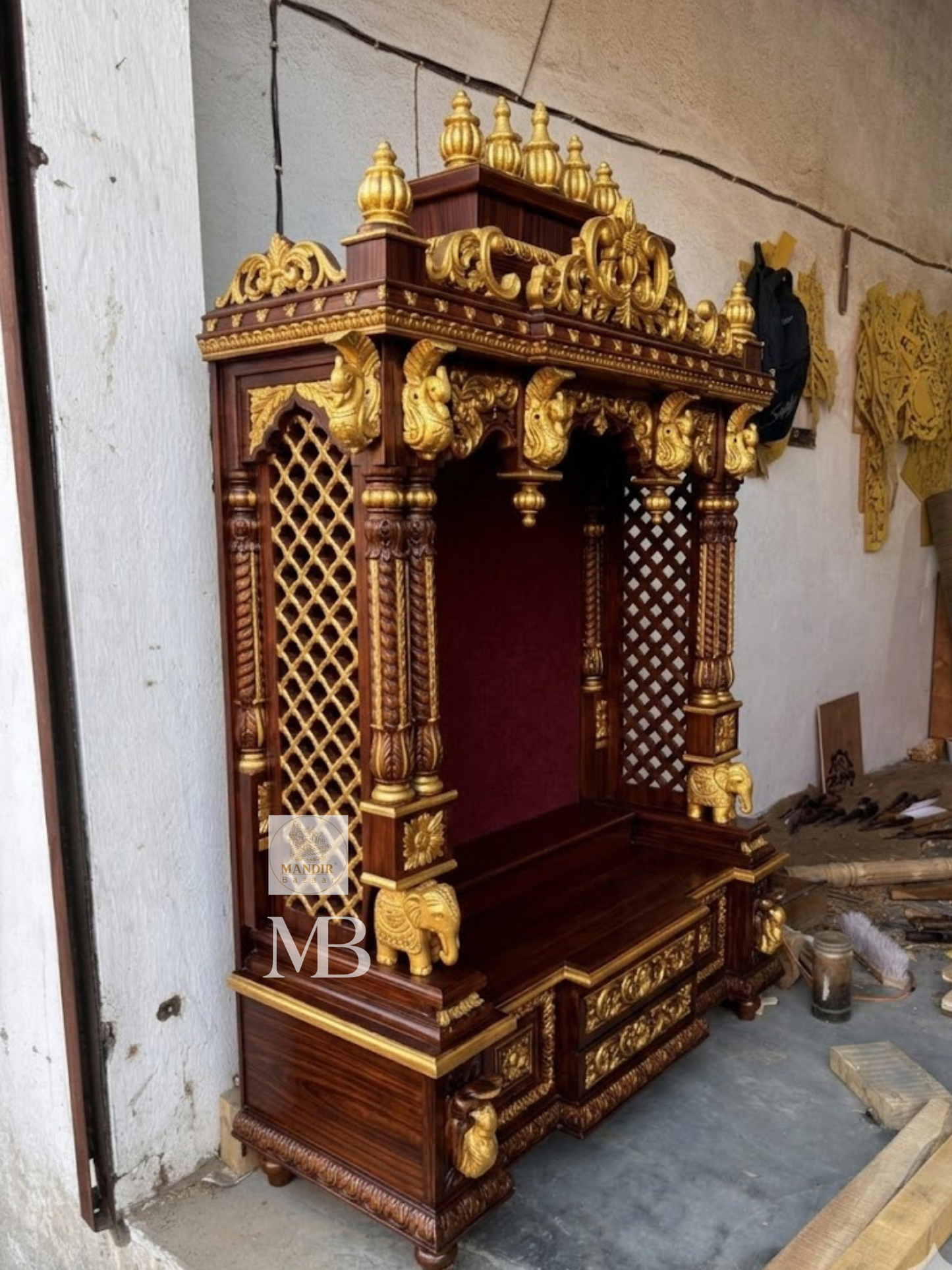 Close up view of hand-carved golden sculpted elephant pillar base on Sheesham wood mandir