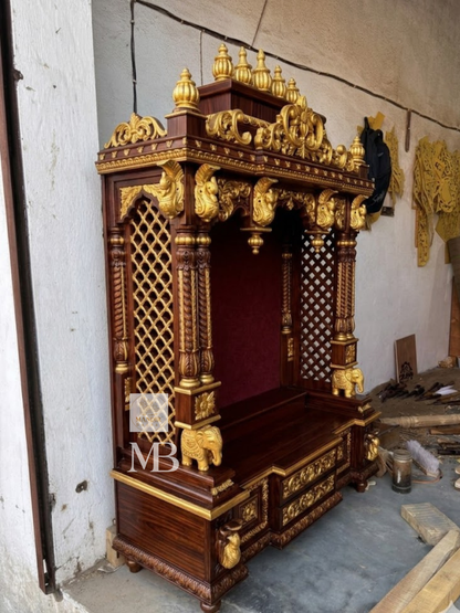 Close up view of hand-carved golden sculpted elephant pillar base on Sheesham wood mandir