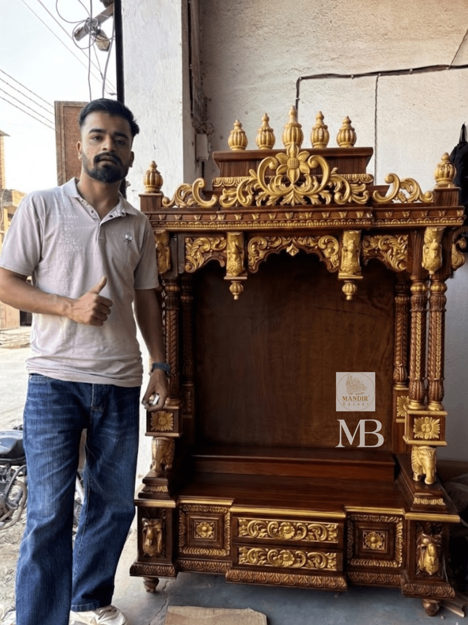 Detailed close up of golden kalash finials and hand-carved floral arch crown on dark wood temple