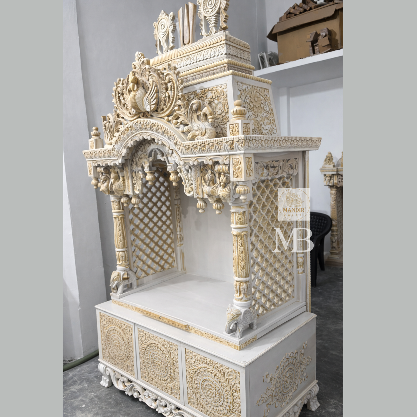 Luxury Sheesham wood home temple showing white and gold hand carved jaali panels, pillars and elephant details