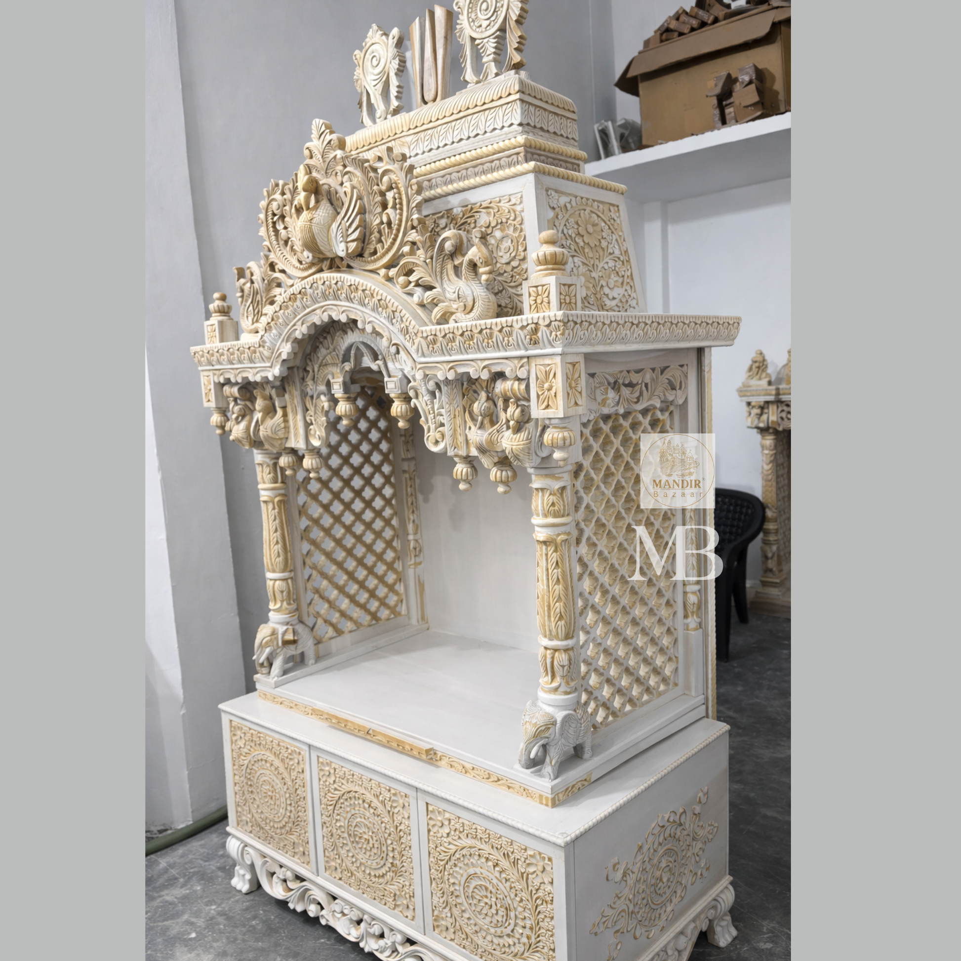 Luxury Sheesham wood home temple showing white and gold hand carved jaali panels, pillars and elephant details