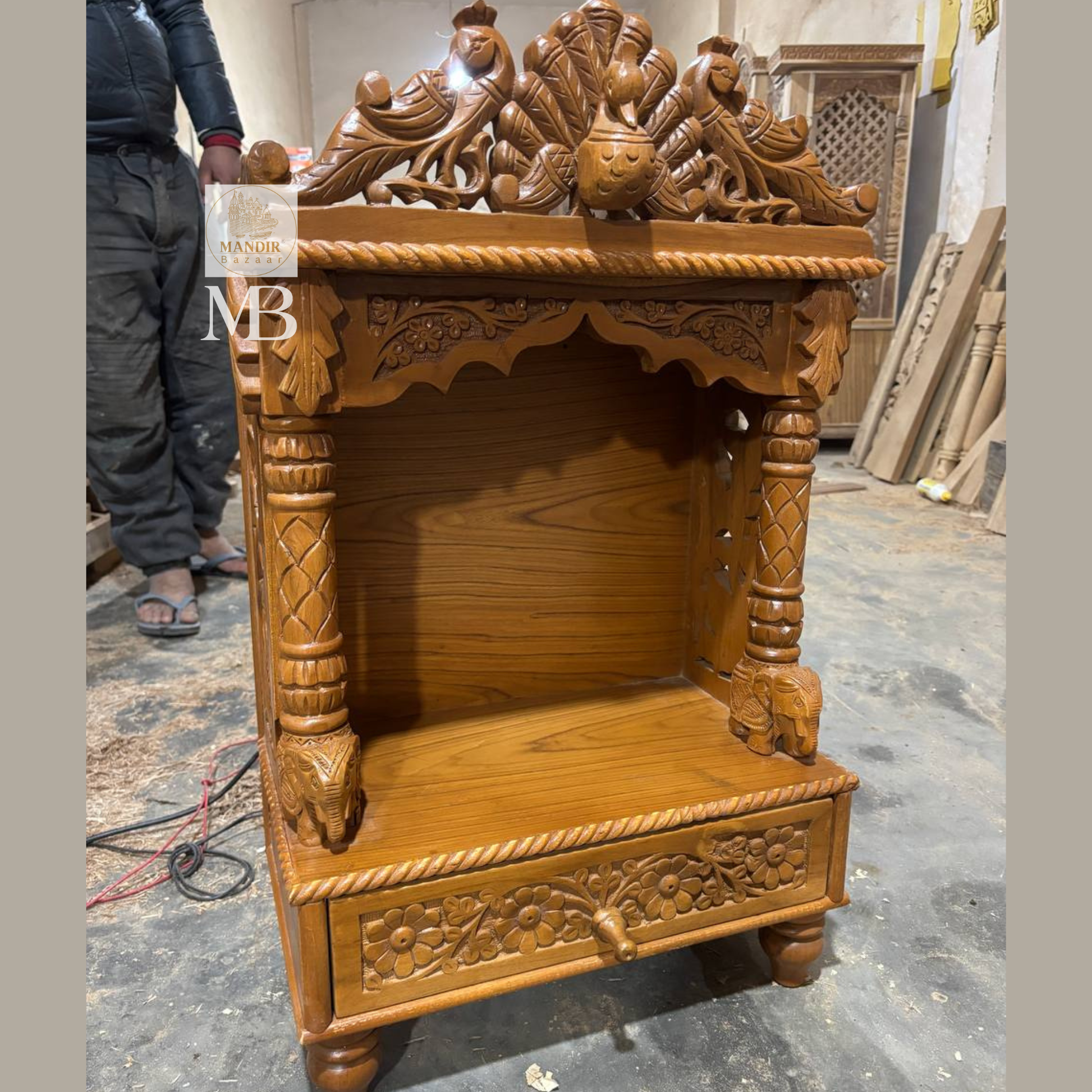 Side perspective view of Sheesham wood tabletop temple highlighting carved peacock side jali panel and elephant pillar