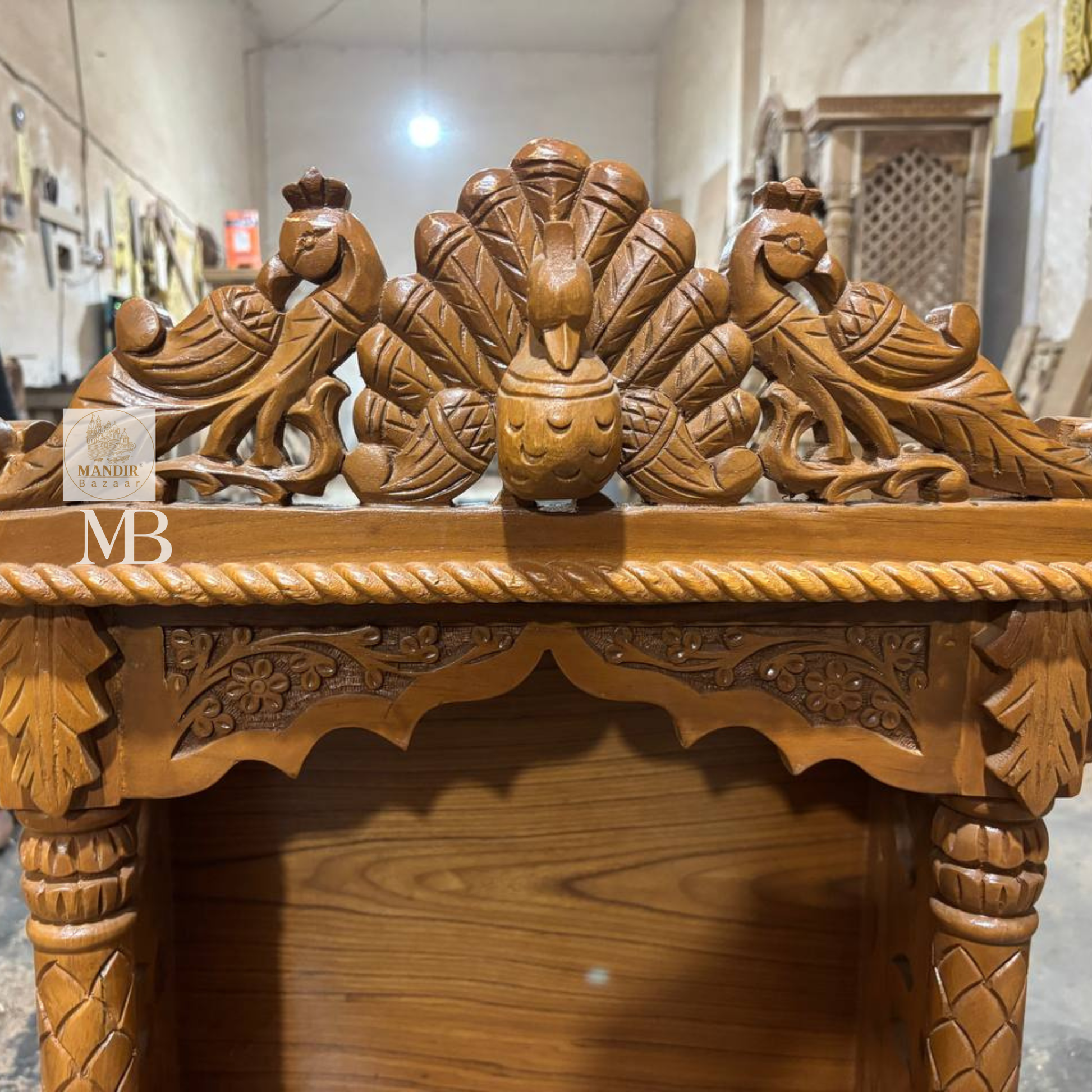 Close up view of hand-carved dancing peacock crown and scalloped floral archway on Sheesham wooden temple