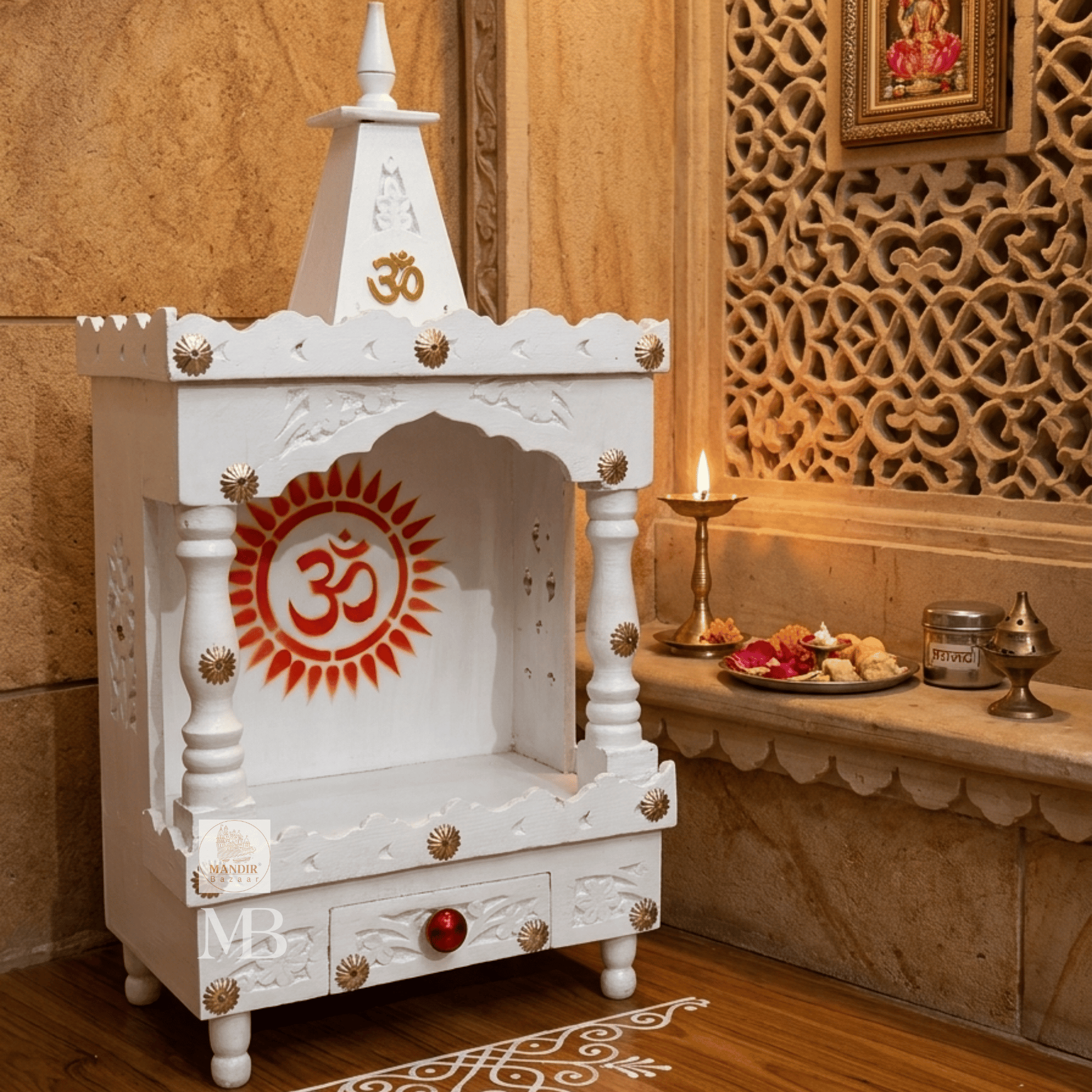 A white carved wooden Shiva mandir altar with red and gold Om symbols, set in a warm, traditional Indian room next to a carved stone wall and lit candle.
