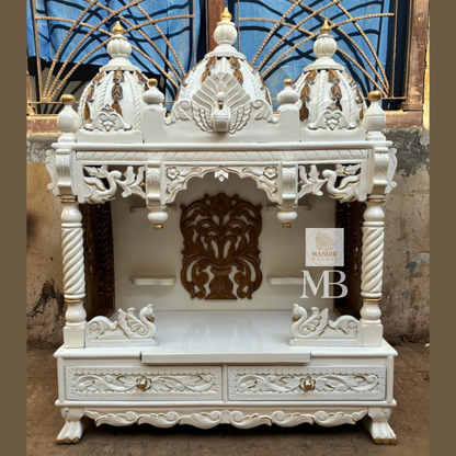Handcrafted white wooden home temple with gold carved highlights and triple peacock domes