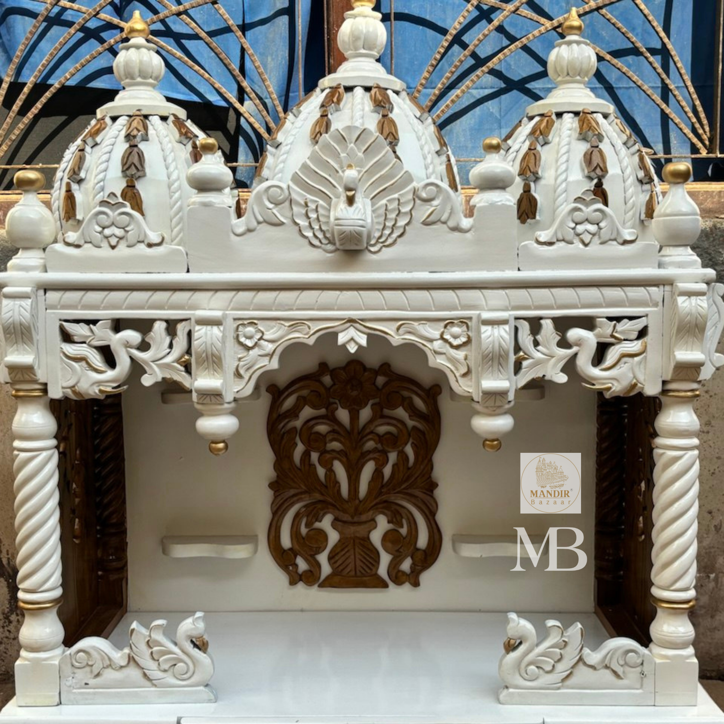 Handcrafted white wooden home temple with gold carved highlights and triple peacock domes
