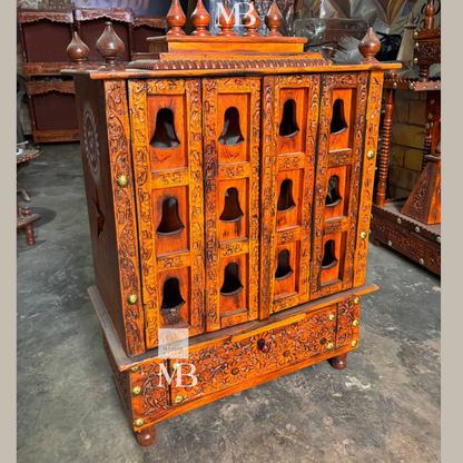 Traditional wooden pooja mandir with carved panels and decorative top