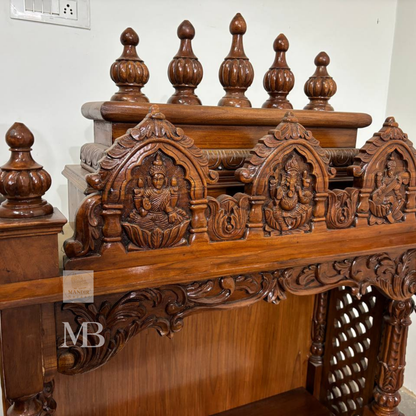 Traditional wooden pooja mandir with carved deity panels and decorative crown
